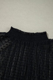 Black sheer mock neck blouse with textured dots and smocked neckline.