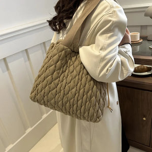Khaki quilted drawstring carryall bag with textured pattern and canvas strap.