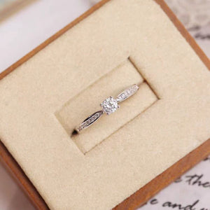 Sterling silver ring with a round moissanite center stone and accent stones.