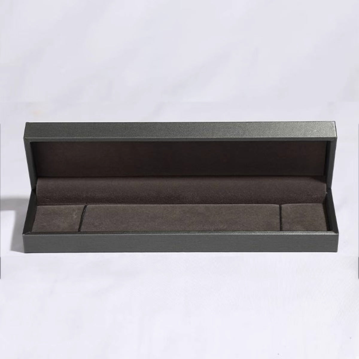 Open dark gray jewelry box with brown velvet lining for a bracelet.