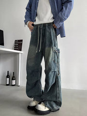 Relaxed fit blue denim cargo jeans with drawstring waist and zippered pocket detail.