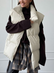 Padded collarless puffer vest in Dust Storm with zip front, worn over a dark sweater and plaid shirt.