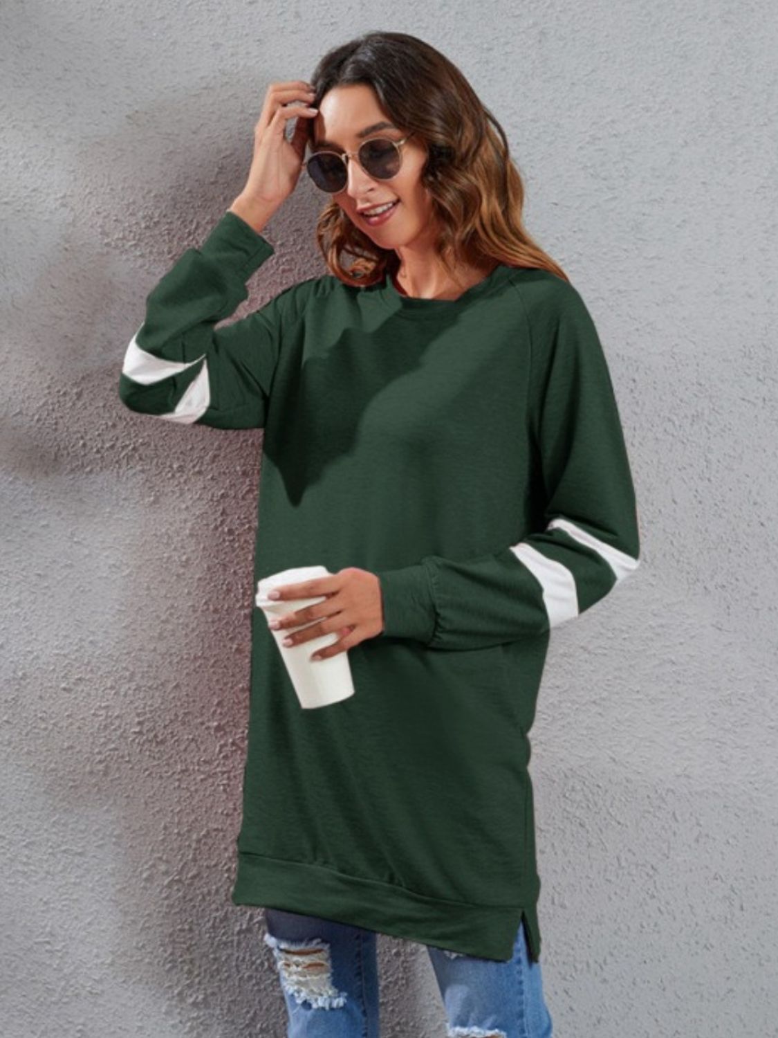 Dark green raglan sweatshirt dress with white varsity stripes on sleeves, crew neck, and side slits.