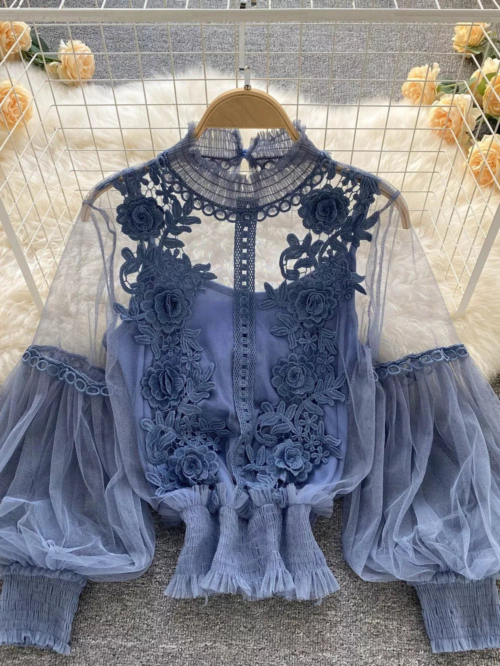 Blue embroidered lace blouse with sheer puff sleeves and ruffled hem, paired with a cami.