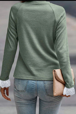 Sage green long sleeve top with lace cuffs and pleated yoke detail.