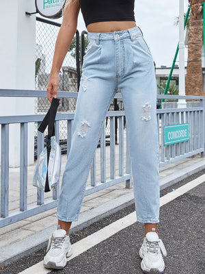 Light wash denim jeans with high rise, pleats, and distressed details.