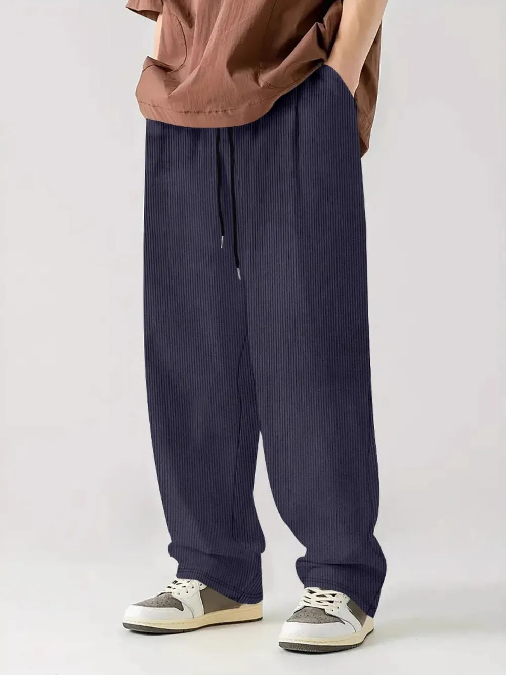 Indigo corduroy relaxed fit trousers with drawstring waist and vertical texture.