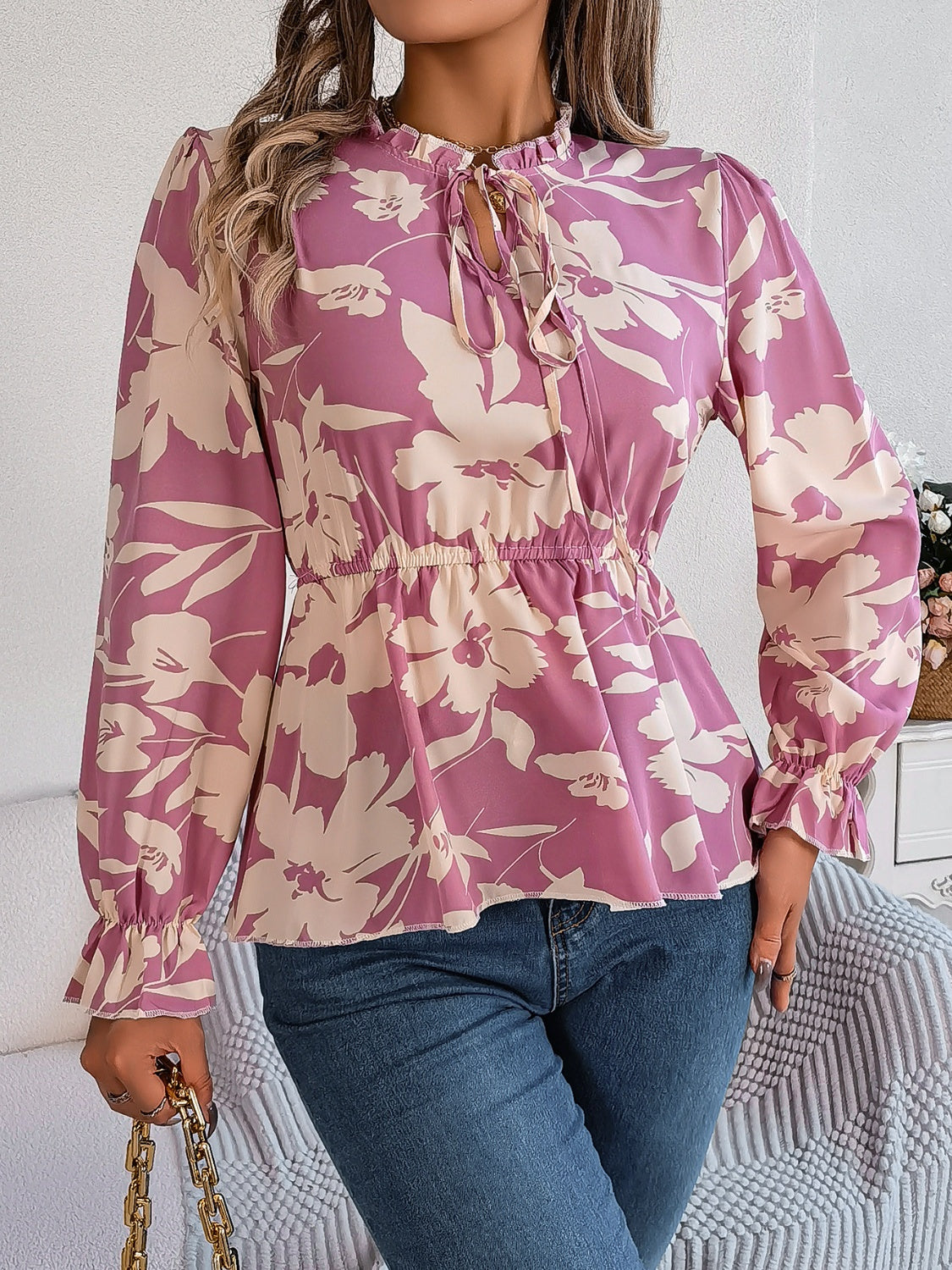 Floral peplum blouse with ruffled neck and tie detail in pink purple, cinched waist, bell sleeves.