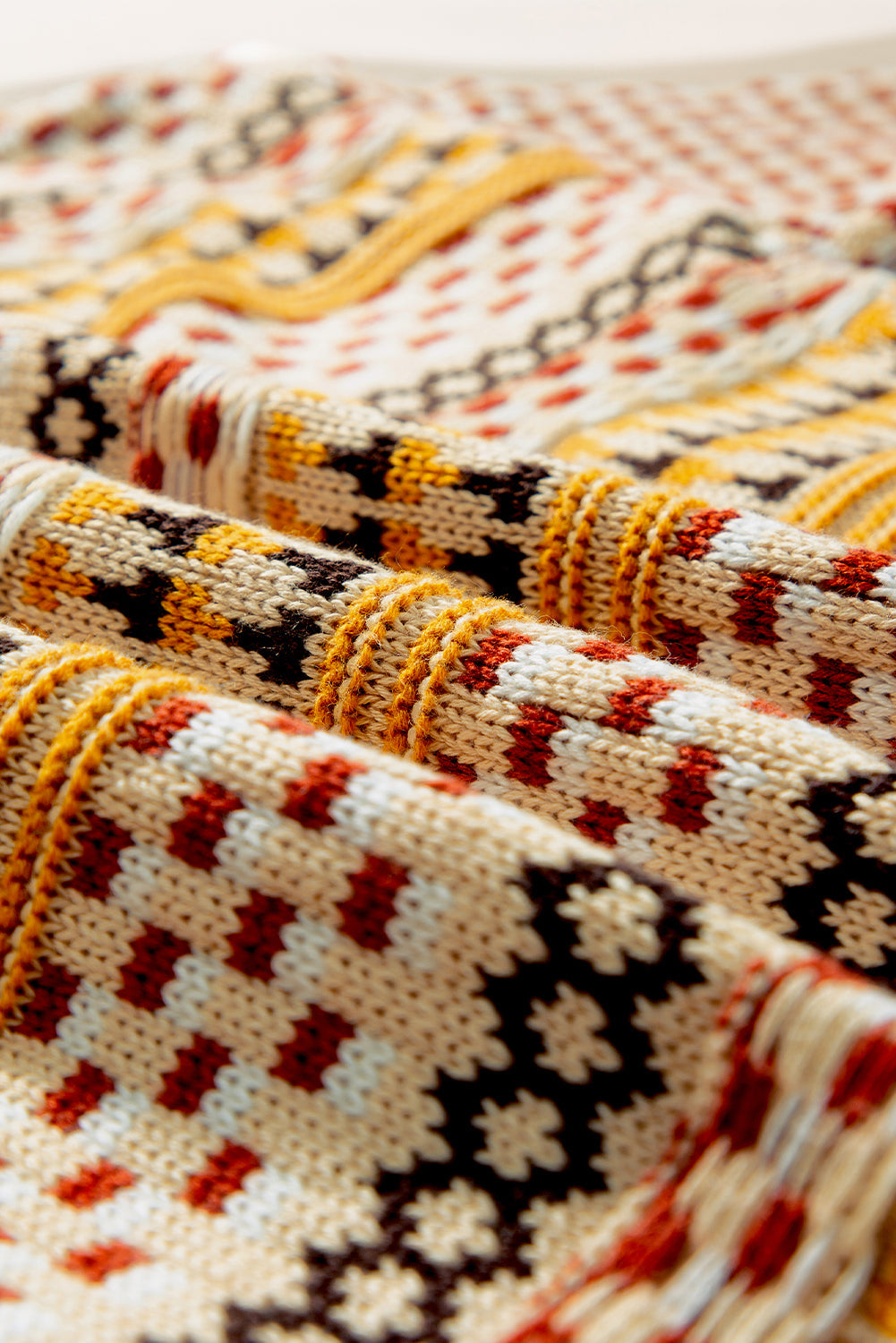 Geometric knit cropped cardigan in cream with tan, rust, and black pattern detail.