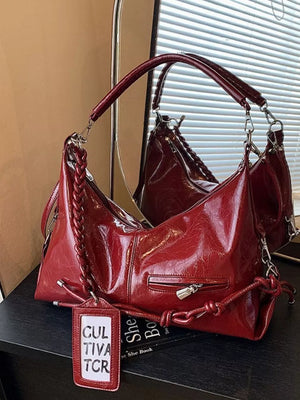 Red vintage-inspired shoulder bag with braided strap detail and zippered pocket.