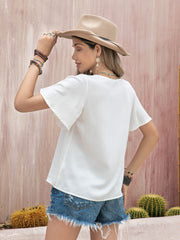 White embroidered medallion blouse with flutter sleeves and a V-neckline.