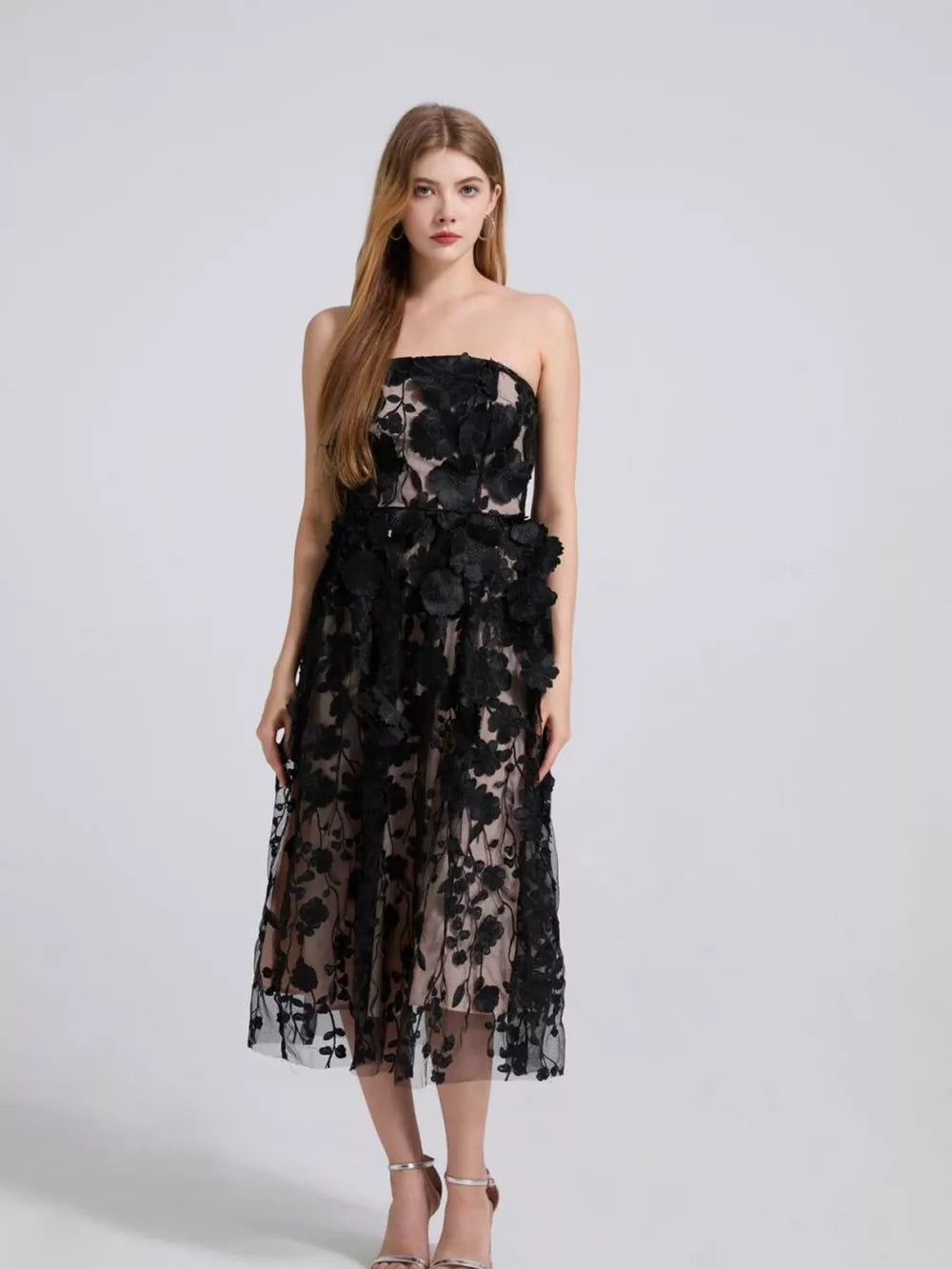 Black strapless midi dress with intricate floral applique and sheer overlay.