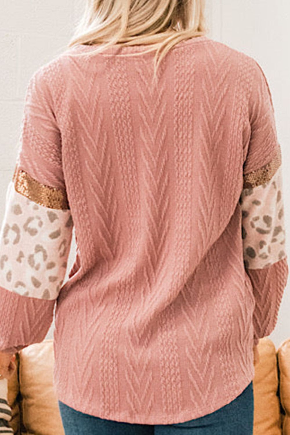 Pale blush sweater with chevron texture, leopard print sleeves, and sequin detail.