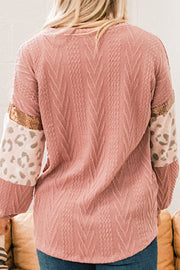 Pale blush sweater with chevron texture, leopard print sleeves, and sequin detail.