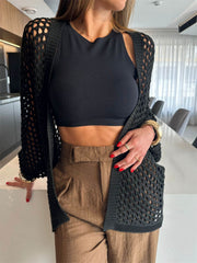 Black open-knit crochet cardigan shrug with relaxed fit and long sleeves.