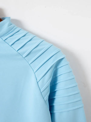 Pastel blue pullover with pleated shoulder detail and zip-neck.