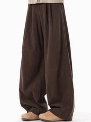 Brown pleated wide leg trousers with a textured fabric detail.