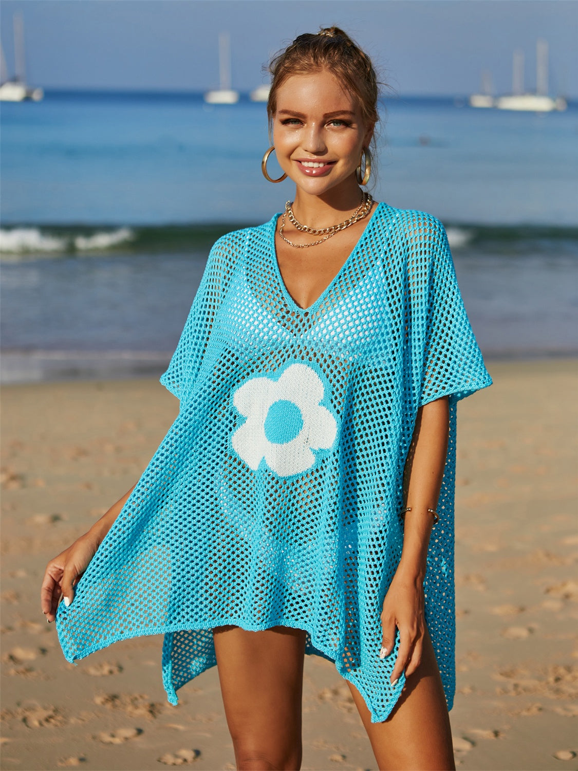 Sky blue crochet beach cover-up with white daisy appliqué and V-neck.