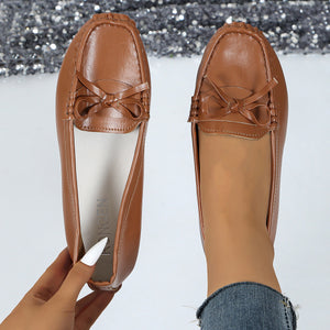 Brown bow embellished flat slip-on loafers with a classic moccasin stitch detail.