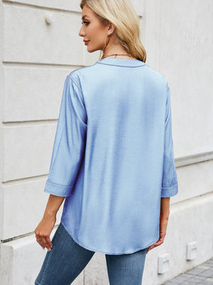 Light blue denim henley blouse with 3/4 sleeves and curved hem.