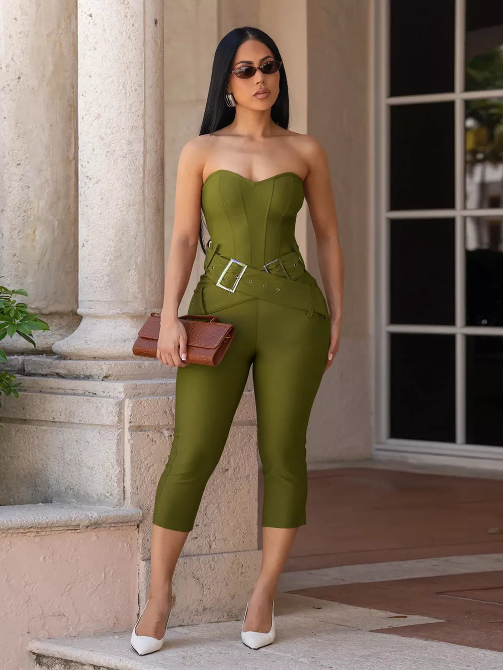 Strapless cinched-waist jumpsuit in moss green with silver buckle belt detail and cropped pants.