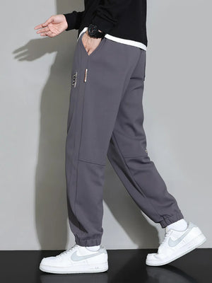 Men's grey cuffed jogger pants with subtle logo detail and pockets.