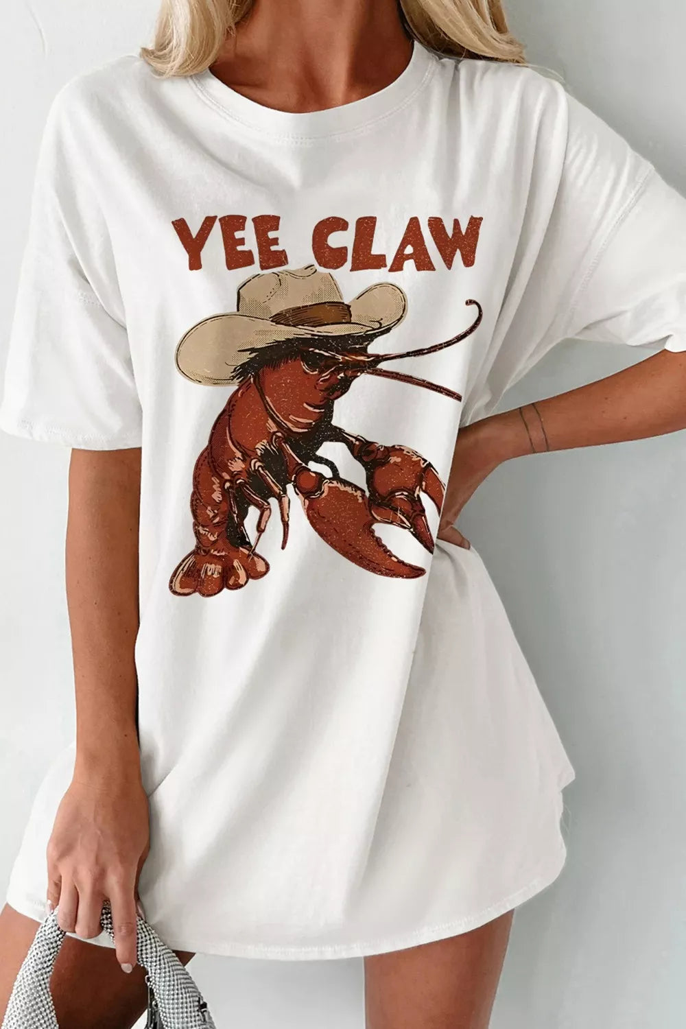 White cotton oversized t-shirt with a cowboy lobster graphic and Yee Claw text.