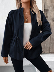 Navy utility jacket with cinched waistline and zip front, styled with a white tank top.