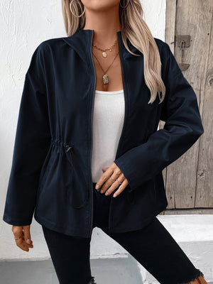 Navy utility jacket with cinched waistline and zip front, styled with a white tank top.