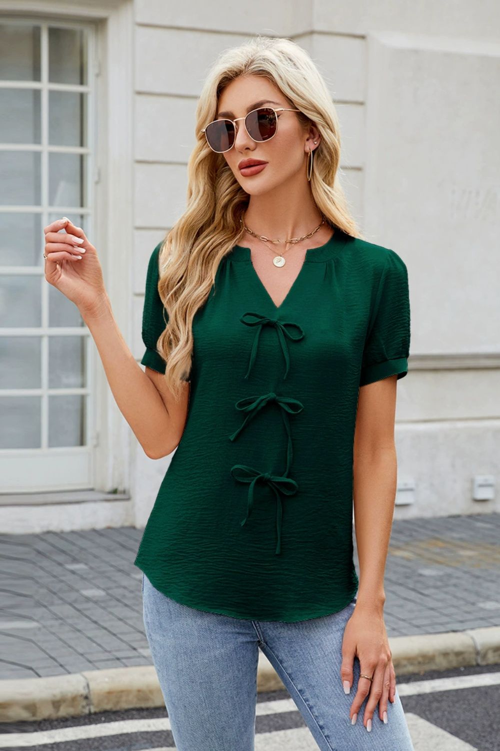 Dark green textured V-neck blouse with three bow details down the front.
