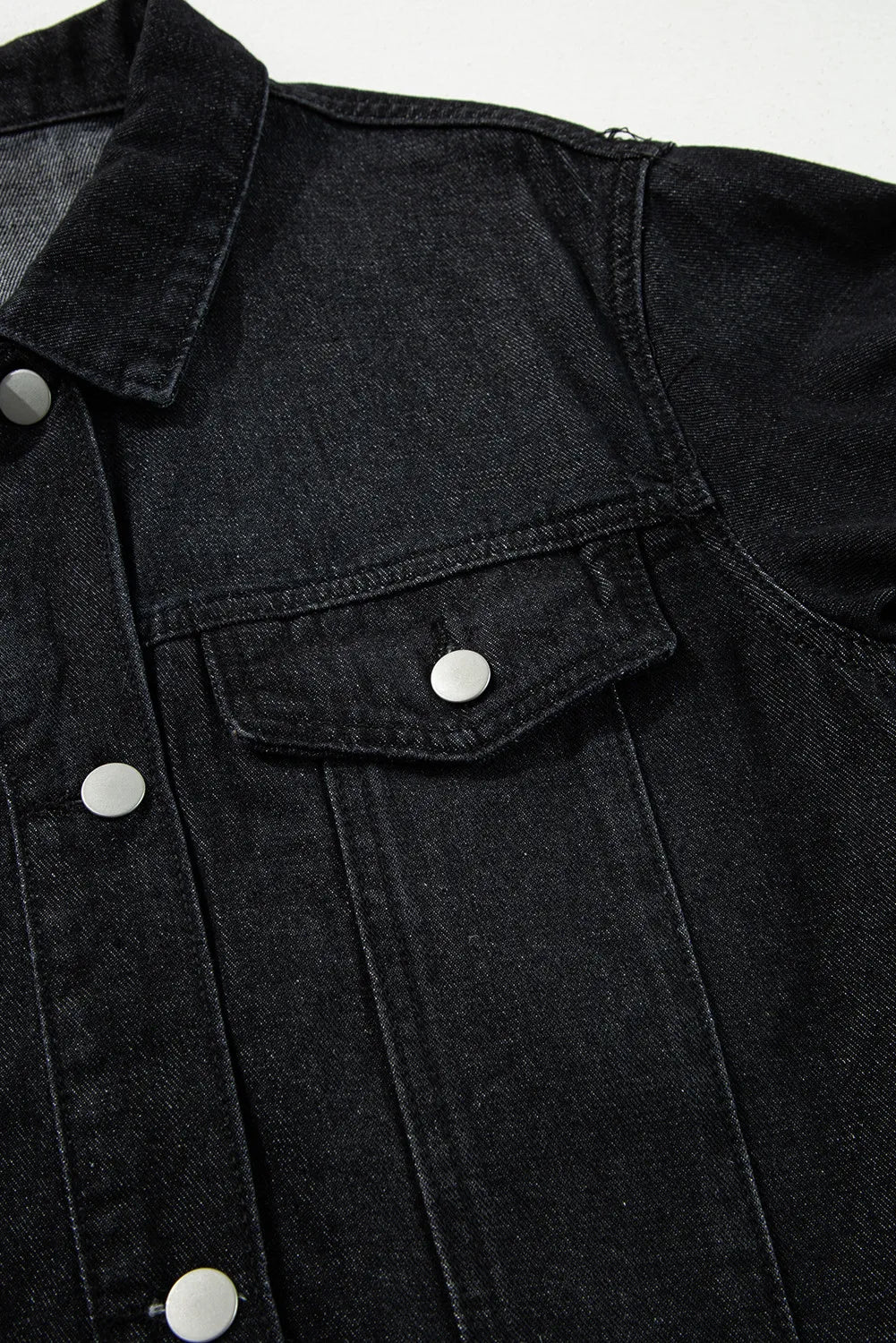 Black denim trucker jacket with silver buttons and chest pocket detail.