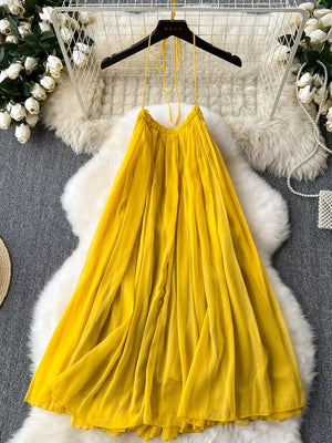 Yellow backless halter maxi dress with flowy pleated skirt.