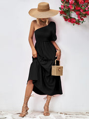 Black one-shoulder tiered dress with smocked bodice and ruffled hem.