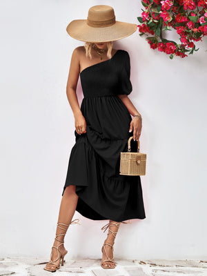 Black one-shoulder tiered dress with smocked bodice and ruffled hem.