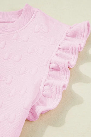 Blush pink loungewear set with embossed bow pattern and ruffle sleeves.