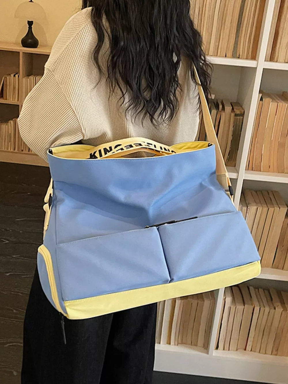 Blue and yellow Oxford cloth travel bag with exterior pockets and a printed strap.