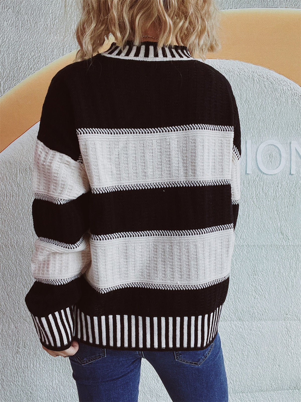 Black and white striped mock neck sweater with textured knit details.