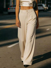 Cream high-waisted pleated wide-leg maternity trousers with button closure.