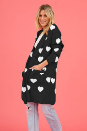 Black acrylic longline cardigan with white heart motif and pockets.