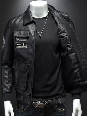 Black leather bomber jacket with patches and chest pockets, open front showing black shirt and necklace.