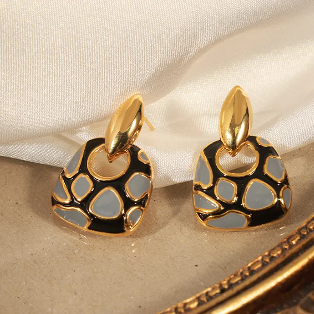 Geometric enamel drop earrings with gold accents and a black and grey abstract pattern.