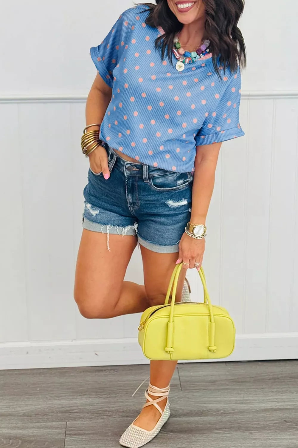 Blue ribbed knit tee with pink polka dots, cuffed short sleeves, and a crew neck.