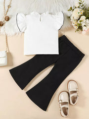 White ruffle-trimmed top with black trim and black flare pants.