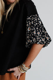 Black t-shirt with daisy print puff sleeves and a round neckline