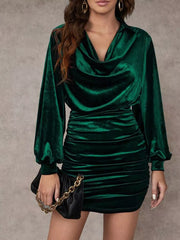 Elegant ruched velvet mini dress with cowl neck and long sleeves in dark green.