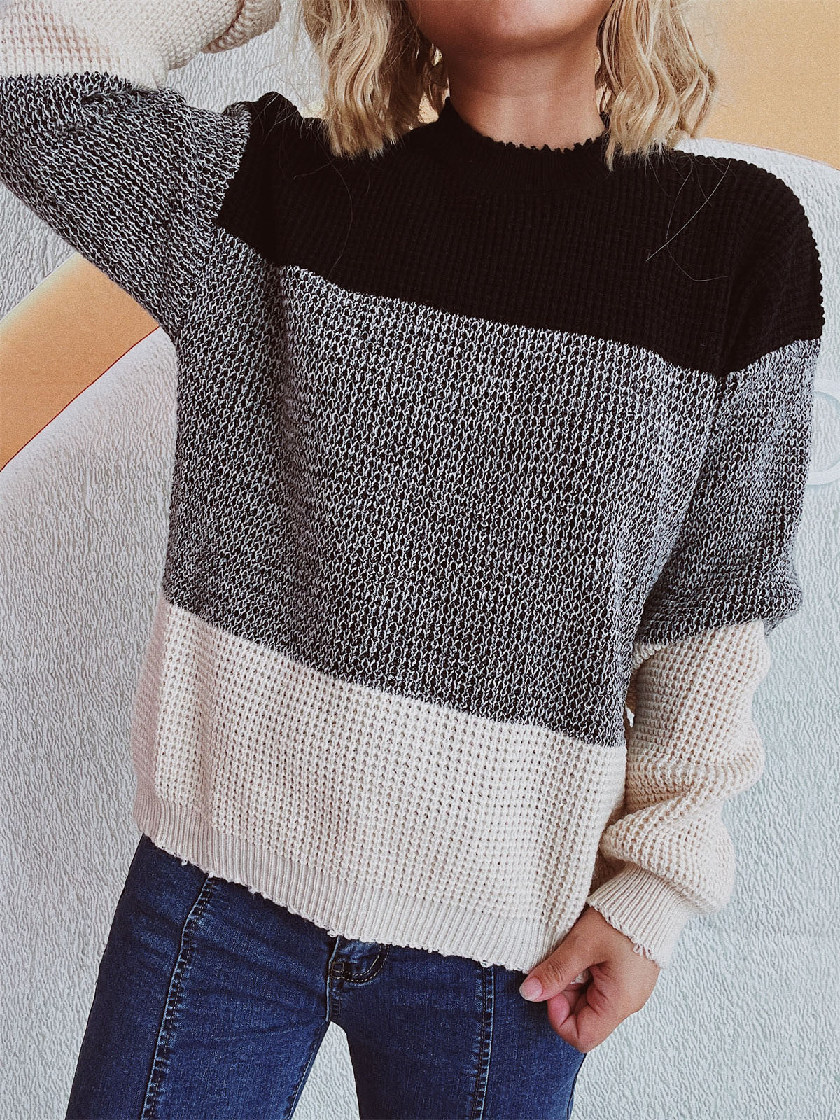 Colorblock knit pullover sweater with textured fabric in black, grey, and cream.