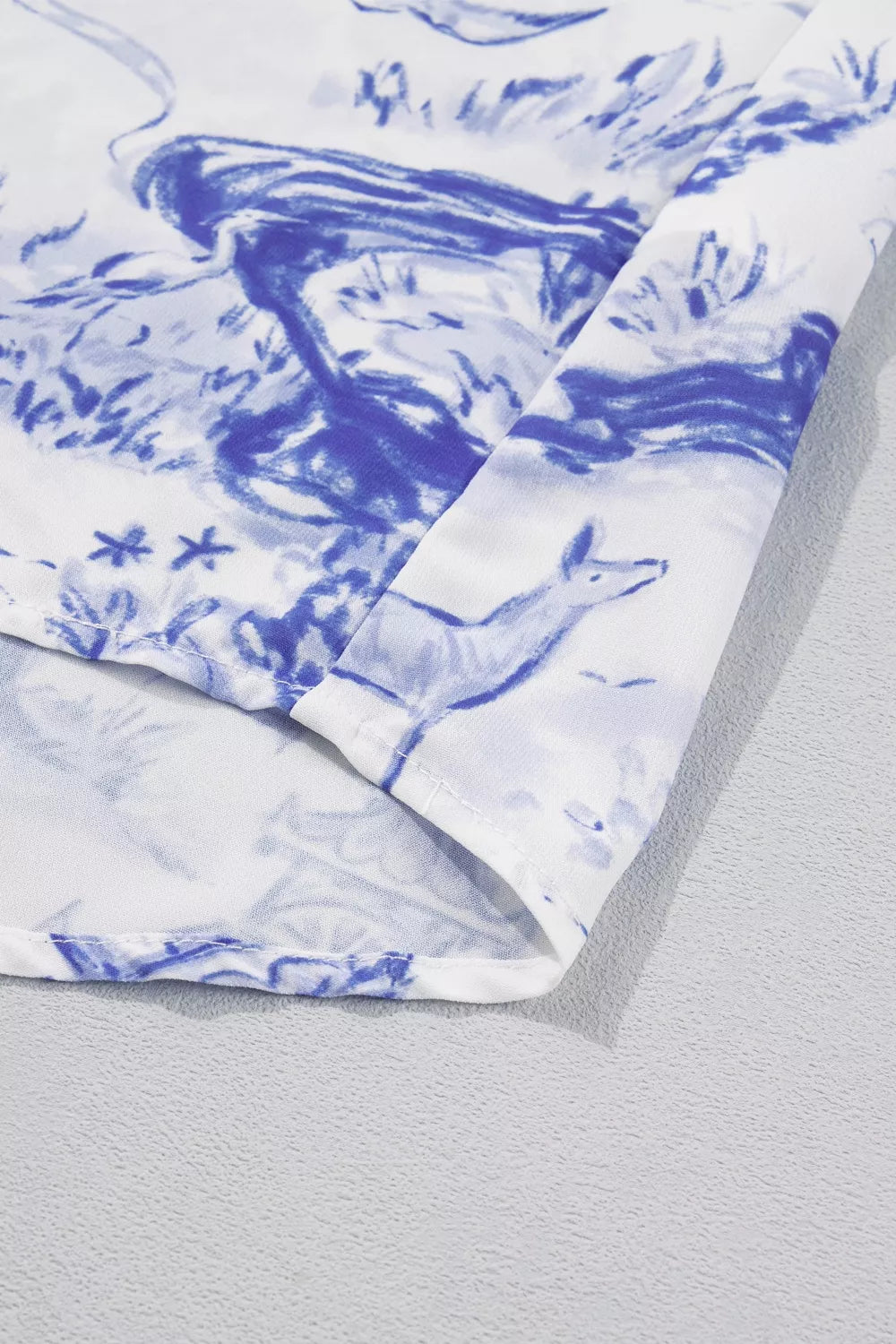 Blue toile print V-neck blouse with a flowing silhouette and detailed stitching.