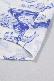 Blue toile print V-neck blouse with a flowing silhouette and detailed stitching.