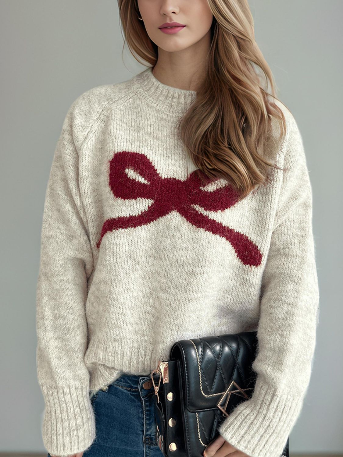Beige knit sweater with red bow intarsia pattern, crew neck, long sleeves.
