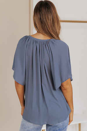 Dusty Blue relaxed V-neck blouse with cap sleeves and gathered neckline detail.